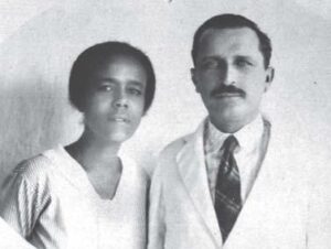 Maria Odília Teixeira, vestida de branco, ao lado de um homem, no Conselho Regional de Medicina da Bahia